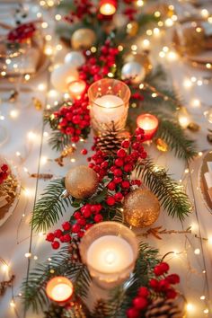 a long table with candles, pine cones and red berries is decorated with christmas decorations