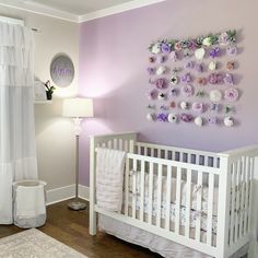 a baby's room with purple walls and white crib, flowers on the wall