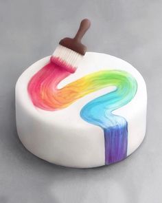 a cake with a brush painted on the top and rainbow swirls in the middle