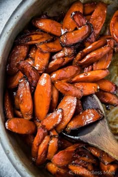 the carrots are being cooked in the pot with a wooden spoon on the side