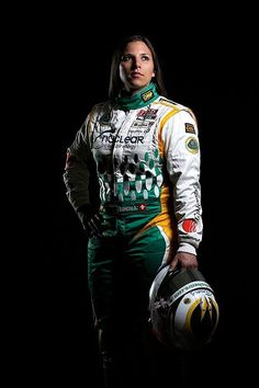 a woman in a racing suit holding a helmet