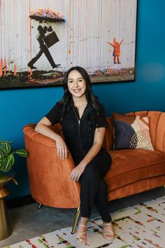 Professional therapist smiling and posing on an orange couch in front of a painting on a blue wall. Therapist Headshots Mental Health, Leadership Photography, Branding Headshots, Boho Branding