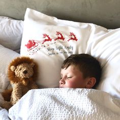 a young boy sleeping in bed with his teddy bear