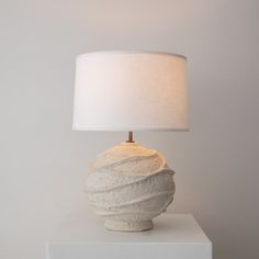 a white lamp sitting on top of a table next to a white box with a light on it