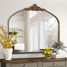 a large mirror sitting on top of a dresser next to a vase filled with flowers