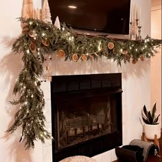 a living room decorated for christmas with garland and lights on the fireplace mantels