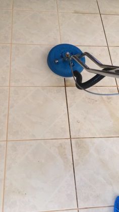 a tile cleaning machine on the floor with a blue brush in it's hand