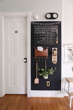 a chalkboard with some plants hanging on it and a clock above the door to the other room