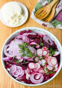 a bowl filled with sliced radishes next to a wooden spoon and white sauce