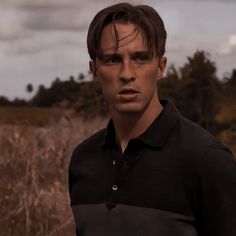 a young man in a black shirt is standing in the middle of a field with tall grass