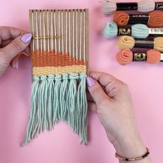 two hands are working on an weaving project with yarns and crochet hooks