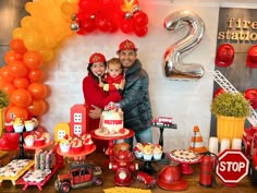 a man and woman standing in front of a table filled with cakes, balloons and decorations