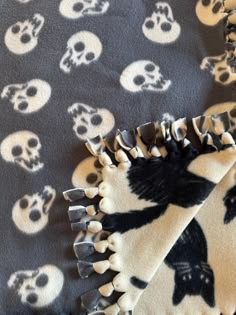 a blanket with skulls on it and a black and white design in the middle is laying down