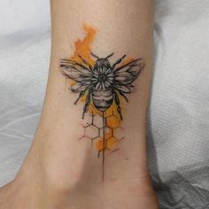 a tattoo on the foot of a woman with a bee and honeycombs design