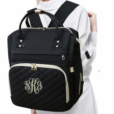 a woman holding a black backpack with monogrammed initials