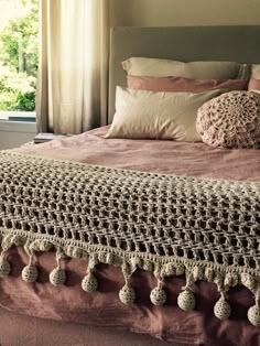 a crocheted bedspread with tassels and pom poms