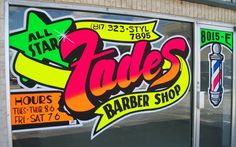 a store front window with some stickers on the glass and door windows that say jade's barber shop