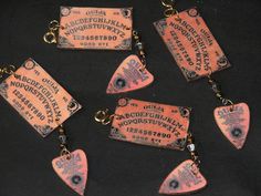 six pink tags with black letters and numbers are hanging from gold chains on a black surface