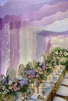 a long table is set with white and purple flowers