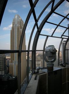 a view from the top of a building looking down at skyscrapers and a telescope