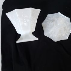 two white vases sitting on top of a black cloth