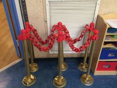 two metal poles with red ribbon on them in front of a door and some bookshelves