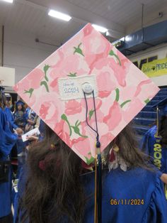 a pink and blue graduation cap with flowers on it is in the middle of a crowd