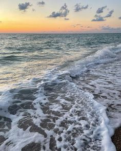 the ocean waves are coming in to shore at sunset with clouds and blue sky above