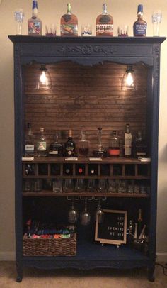 an old fashioned bar with liquor bottles and glasses on the top shelf, in front of a brick wall