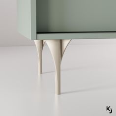 a green cabinet sitting on top of a white floor next to a wooden table with two legs