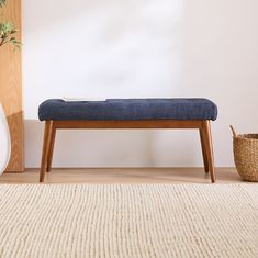 a blue bench sitting on top of a wooden floor next to a white vase and potted plant