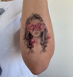 a woman's arm with flowers on it and her face in the middle of the arm