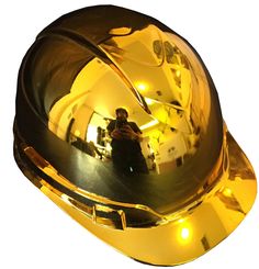 the reflection of a man in a shiny gold helmet is seen through a mirror on a white background