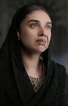 a woman wearing a black shawl and nose ring with an earring on her nose