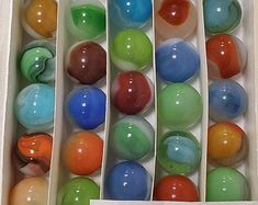 an open box filled with lots of different colored marbles on top of each other