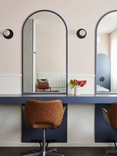 two brown chairs sitting in front of mirrors on top of a blue counter next to a window