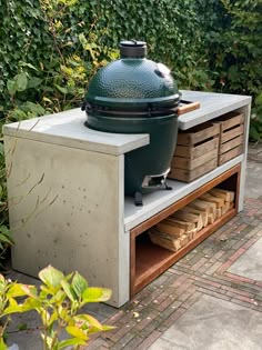 a big green egg sitting on top of a wooden table next to some bushes and trees