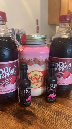 three bottles of liquid sitting on top of a wooden table