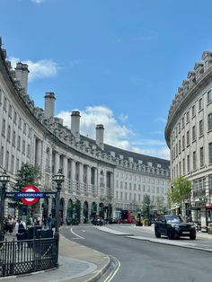 an empty street in the middle of a city with buildings on both sides and cars driving down it