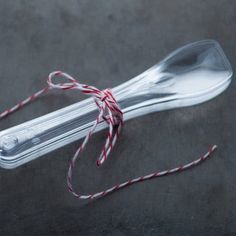 a silver spoon tied with red and white twine on top of a black surface