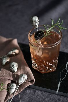 a drink with olives on the side and some silver skulls sitting next to it