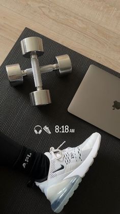 a pair of sneakers and a laptop on a mat with dumbbells next to it