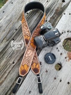 a camera strap with an orange flower pattern on it, next to a pair of binoculars