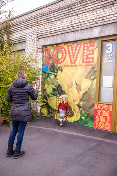 a woman standing in front of a building with a mural on it's side