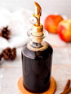 an apple cider sitting on top of a table next to cinnamon sticks and apples