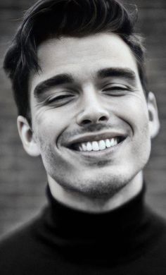 a black and white photo of a young man with his eyes closed smiling at the camera