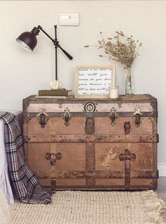 an old trunk sitting on top of a rug next to a lamp