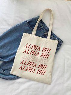 a tote bag sitting on top of a bed next to a pair of jeans