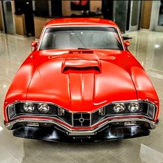 an old red car is parked in a building