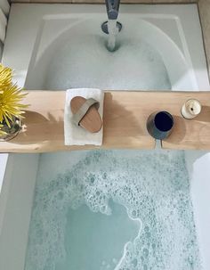 a bathtub filled with water and soap next to a flower pot on the floor